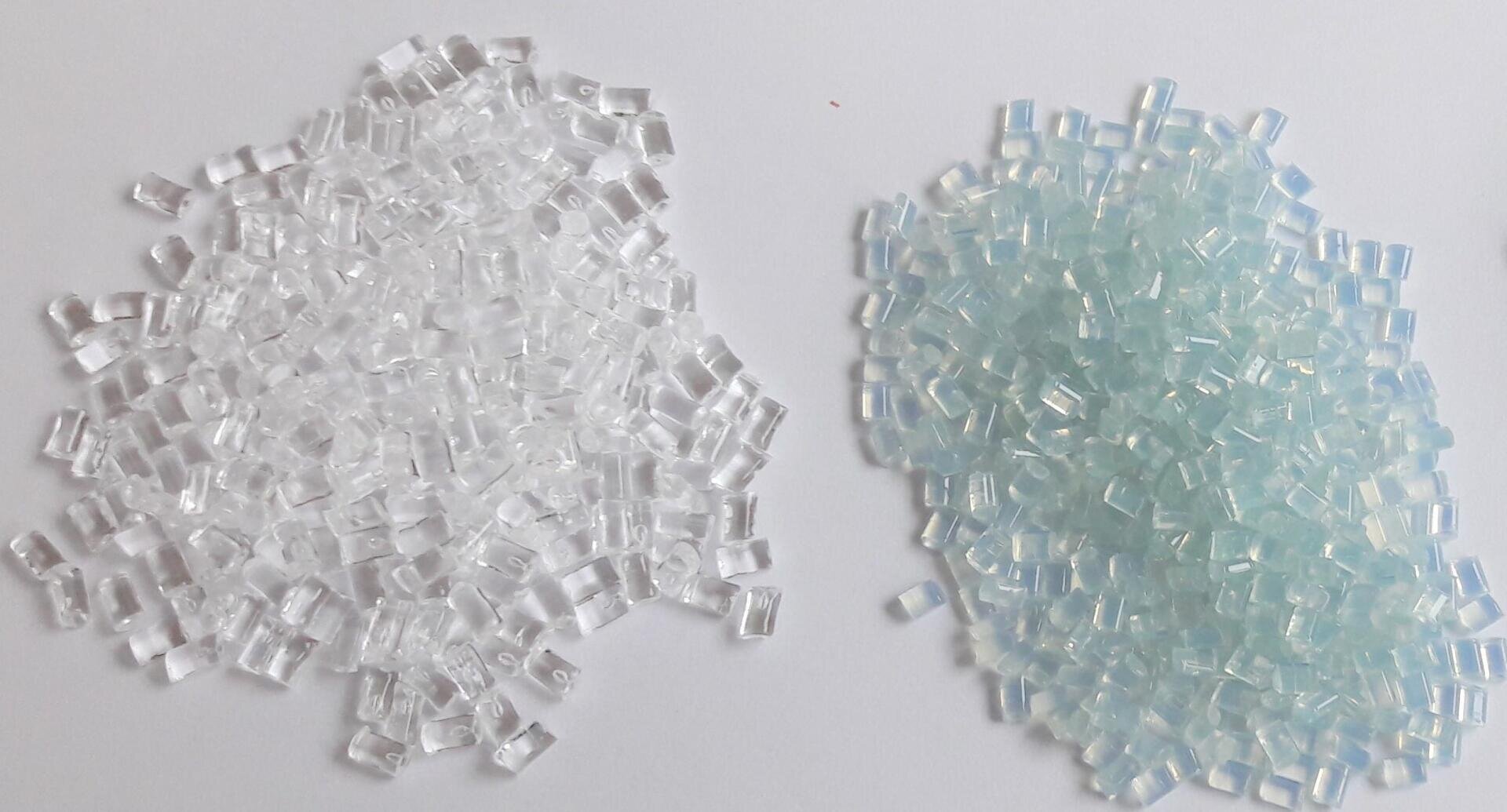 Two piles of small plastic beads on a white surface; the left pile is clear, the right one is light blue and slightly translucent.