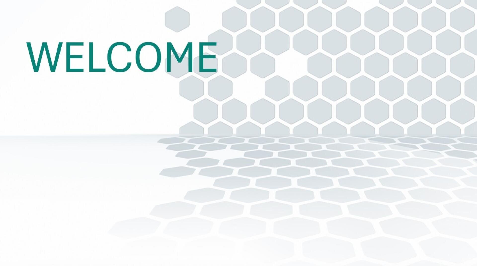 Das Bild zeigt das Wort WILLKOMMEN in grüner Schrift auf der linken Seite, mit einem Hintergrund aus hellgrauen Sechsecken, die nach rechts unten auslaufen, wodurch ein modernes, geometrisches Design entsteht.