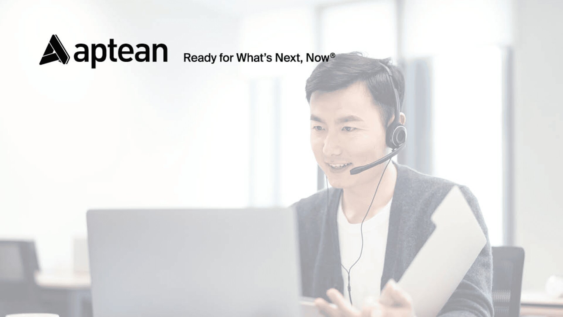 Ein Mann mit Headset sitzt mit einem Laptop an einem Schreibtisch und hält Dokumente in der Hand. Das Aptean-Logo und der Slogan „Ready for Whats Next, Now®“ sind oben links zu sehen. Der Hintergrund ist hell und modern.