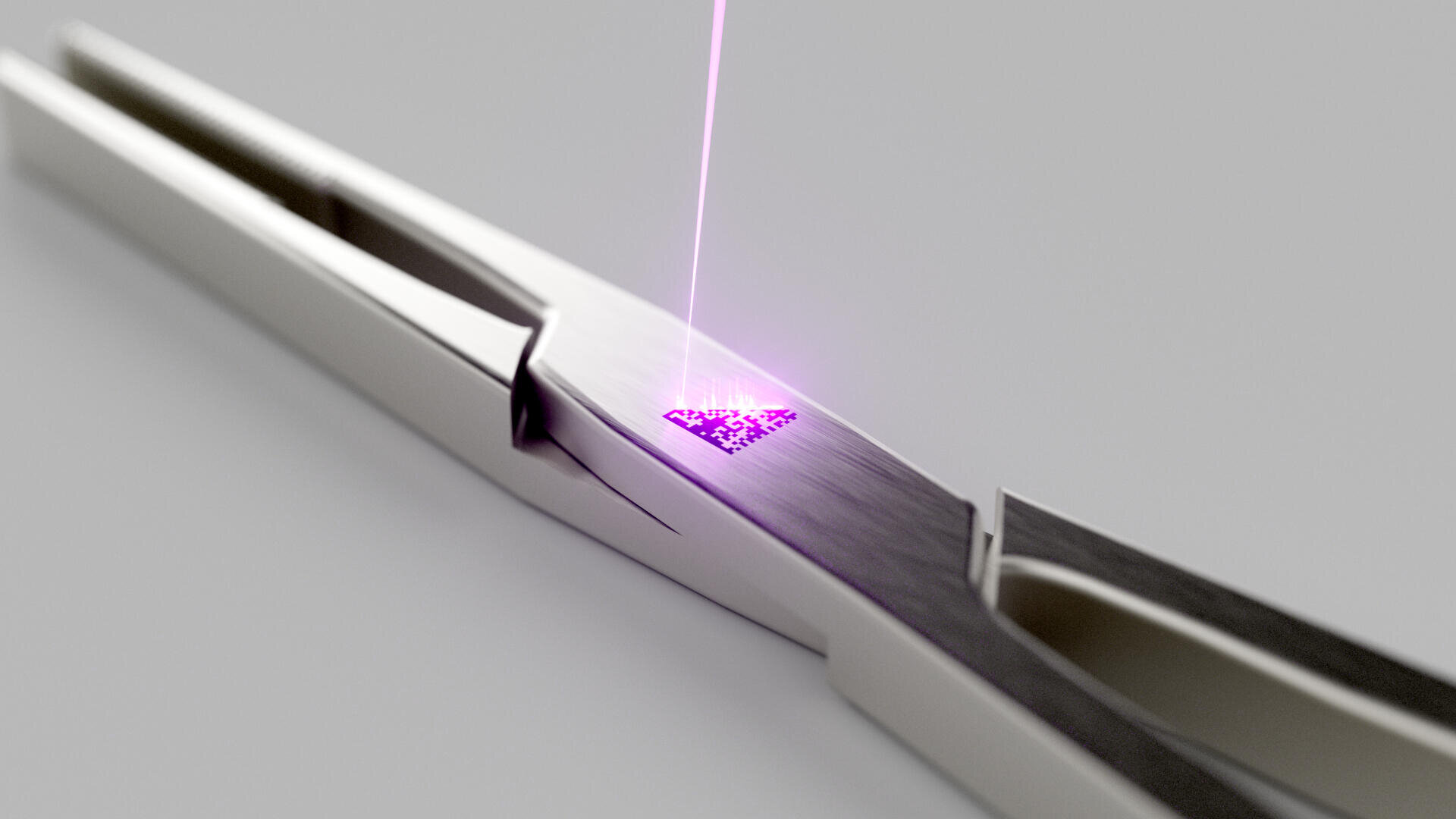 A close-up of a pair of metallic tweezers with a glowing purple laser engraving a QR code onto one of the tweezer arms. The background is plain and light gray.