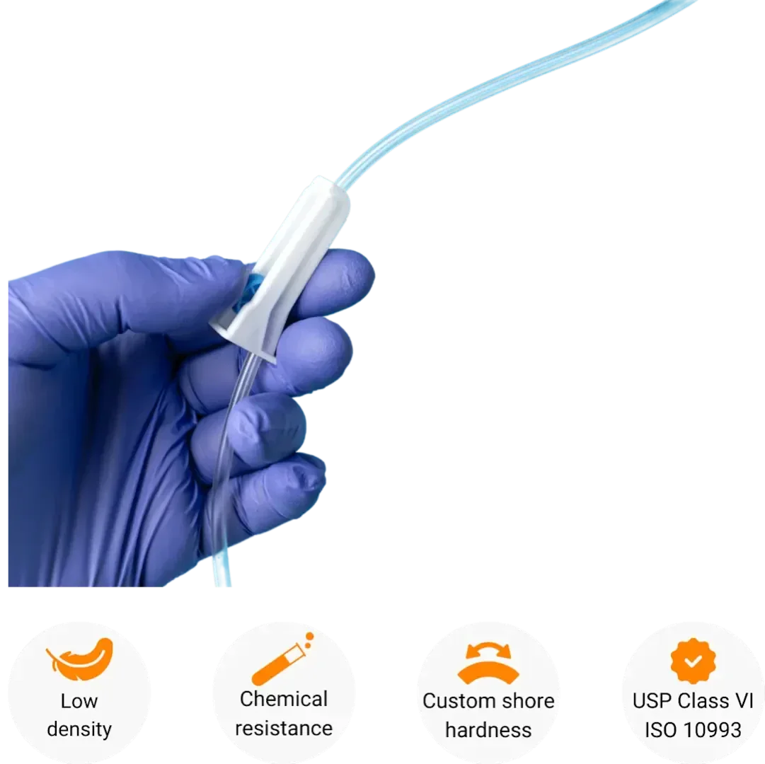 A gloved hand holding a flexible medical tube with a white connector. Below are symbols and text highlighting features: low density, chemical resistance, custom Shore hardness, and compliance with USP Class VI ISO 10993.