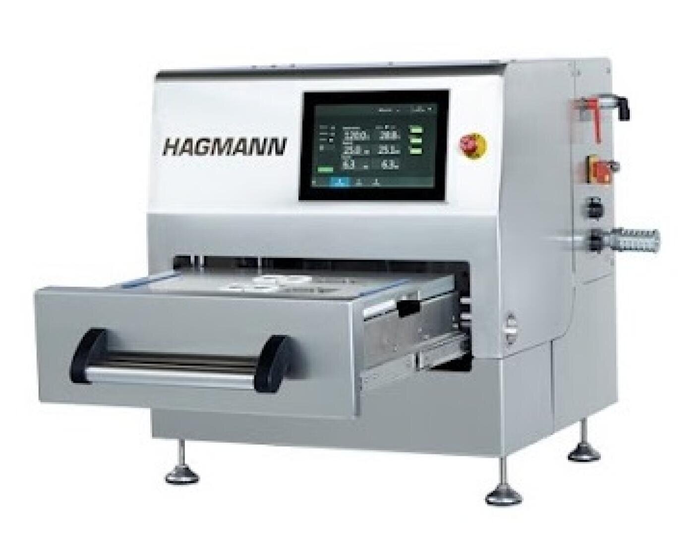 Eine silberne HAGMANN-Industriemaschine mit Touchscreen-Display, Bedientasten und offener Frontschublade, die auf vier Beinen steht.