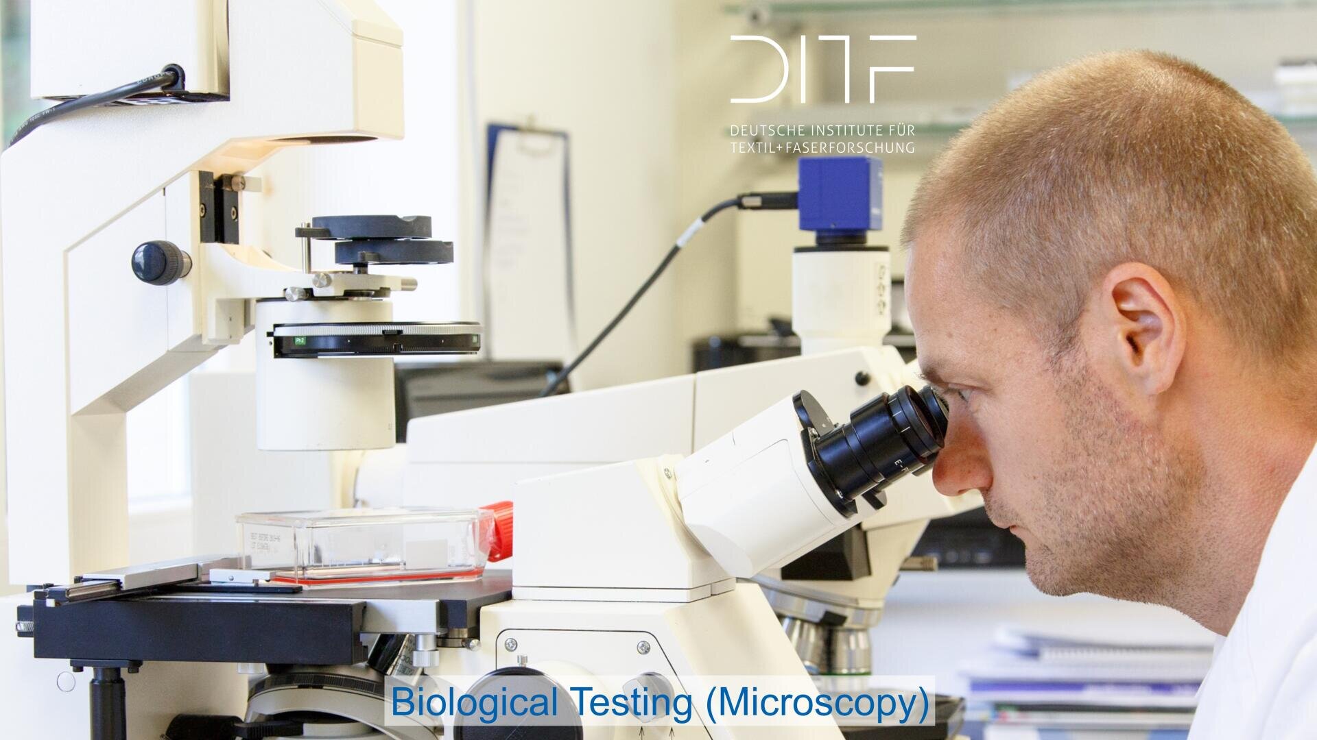 A man looks into a microscope in a laboratory setting, with lab equipment and a sample dish visible. The text Biological Testing (Microscopy) appears at the bottom, and a logo with DITF is in the background.
