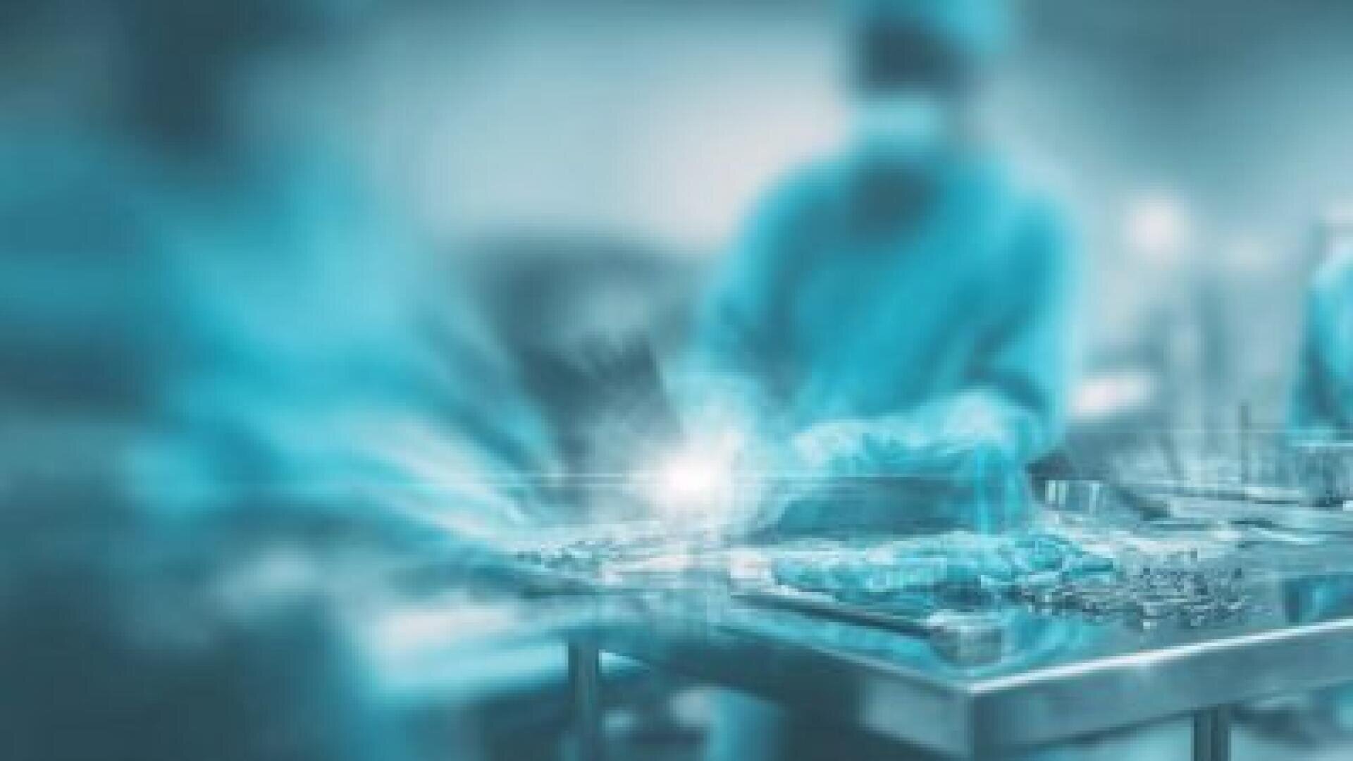 Blurred image of surgeons in gowns and masks performing an operation in an operating room, with surgical instruments lying on a metal table in the foreground.