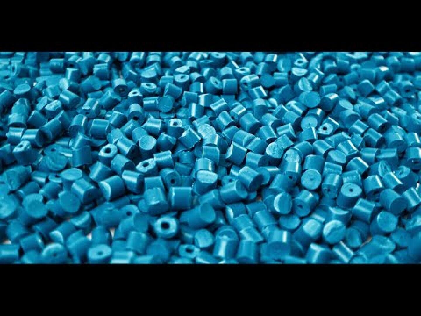 Ein großer Haufen kleiner, zylindrischer, blauer Plastikkügelchen, die dicht beieinander liegen und den größten Teil des Bildes ausfüllen.