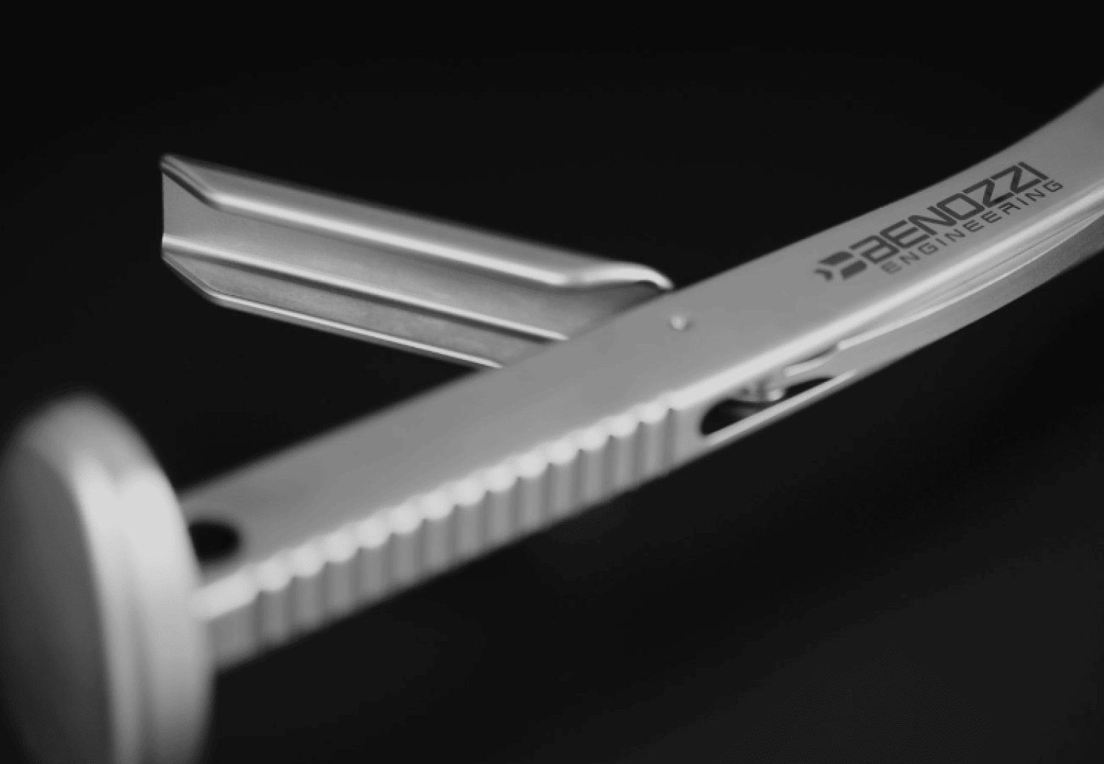 Close-up of a metallic tool with a ridged handle and the brand BENAZZI ENGINEERING etched on it, set against a dark background.
