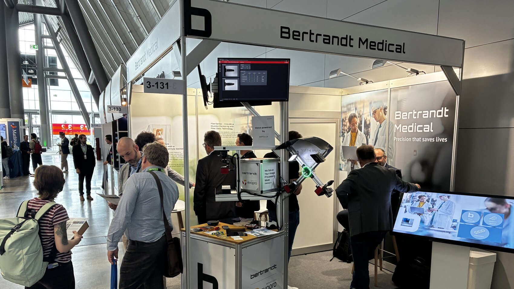 Bertrandt: Edge-AI-Applikation als Blaupause für KI in der Medizintechnik  Ursprünglich aus der Automobilindustrie stammend, überträgt der Entwicklungsdienstleister Bertrandt sein Embedded-Know-how seit einigen Jahren auf die Medizintechnik – mit einer eigenen Medical-Sparte von Elektronik- und Softwareentwicklung über Simulation und Testing bis zur regulatorischen MDR-Begleitung. Auf der MedtecLIVE 2026 stand dabei eine funktionsfähige Edge-AI-Demo im Mittelpunkt: Ein IoT-fähiges Kamera-Modul erfasst einen kritischen Prozess direkt am Point of Care, analysiert die Bilddaten lokal per Deep Learning auf dem Edge-Device und meldet Abweichungen in Echtzeit – die klinische Entscheidung fällt am Ort des Geschehens, nicht nachgelagert in der Cloud.  Edge-First mit optionaler Backend-Anbindung  Die Architektur setzt auf Computer Vision und lokale KI-Inferenz, Datenschutz-by-Design durch ausschließlich lokale Verarbeitung klinischer Daten sowie Schnittstellenfähigkeit zu bestehenden Krankenhausinformations- und Dokumentationssystemen. Technologieneutral und skalierbar ist die Lösung auf verschiedene medizintechnische Anwendungsfelder übertragbar – von der bildgestützten Qualitätssicherung in der Fertigung bis zur Prozessüberwachung im OP.  Safety und Security als Entwicklungsprinzip  Requirements Engineering, Softwarearchitektur nach IEC 62304 sowie funktionale Sicherheit nach ISO 26262 und Cybersecurity by Design nach ISO/SAE 21434 sind bei Bertrandt keine nachträglichen Compliance-Maßnahmen, sondern werden von Tag eins in die Systemarchitektur eingebettet – eine Anforderung, die Benannte Stellen bei KI-basierten Medizinprodukten zunehmend explizit einfordern.